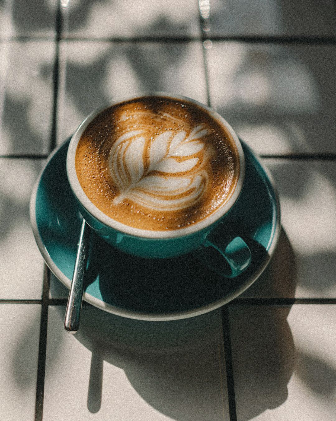 A cup of coffee with a leaf cream design with soft morning light. A Soft Start Morning Rituals for Nervous System Wellness.