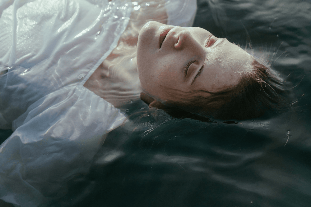 Image of woman floating in water with white linen clothing