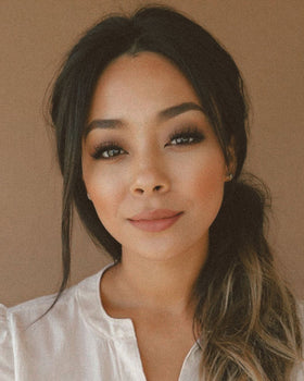 An amber candle labeled Morning Affirmations by Alchemist + Co. in front of a coffee maker and can of ground coffee