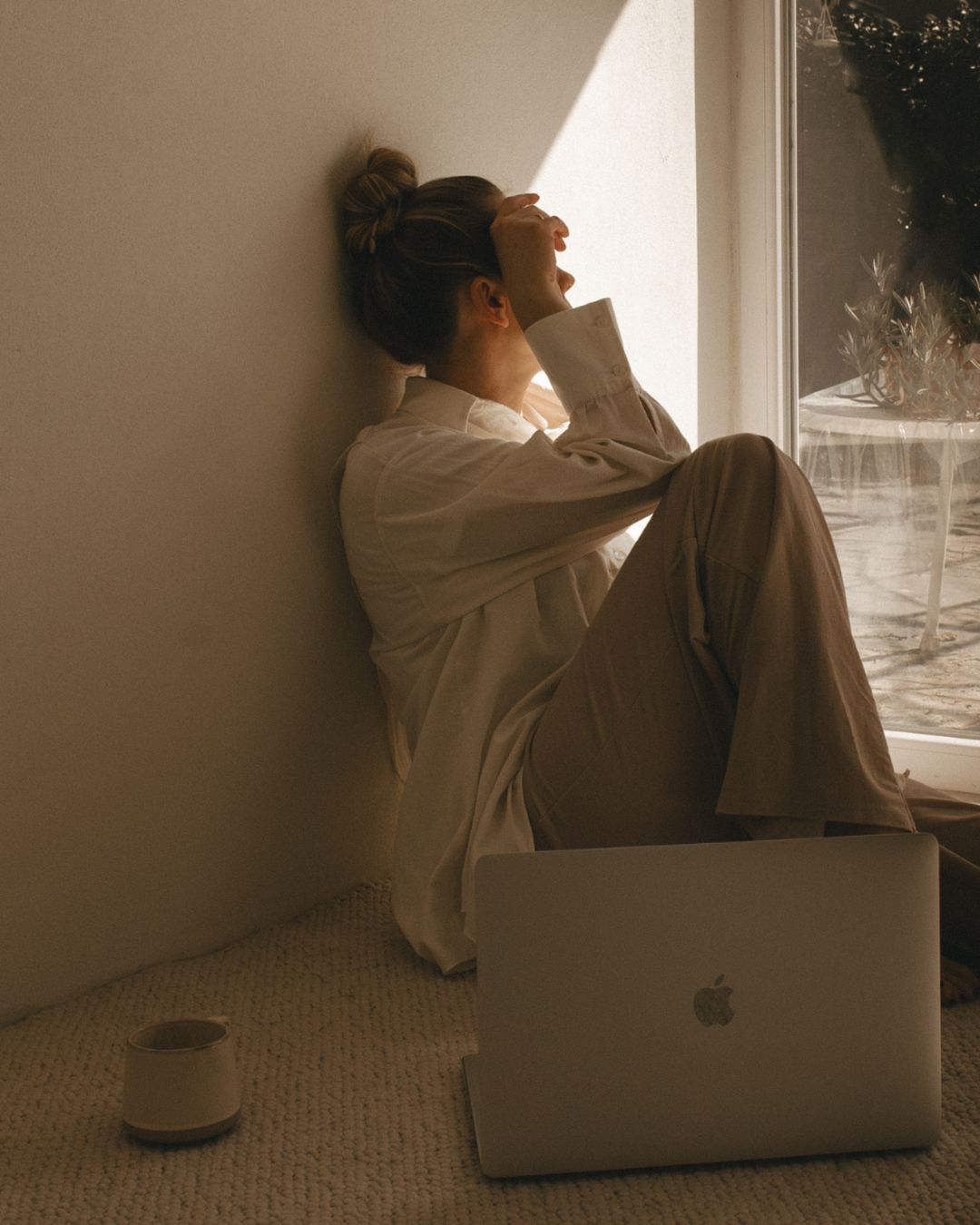 Editorial image of a pensive woman with coffee and a laptop