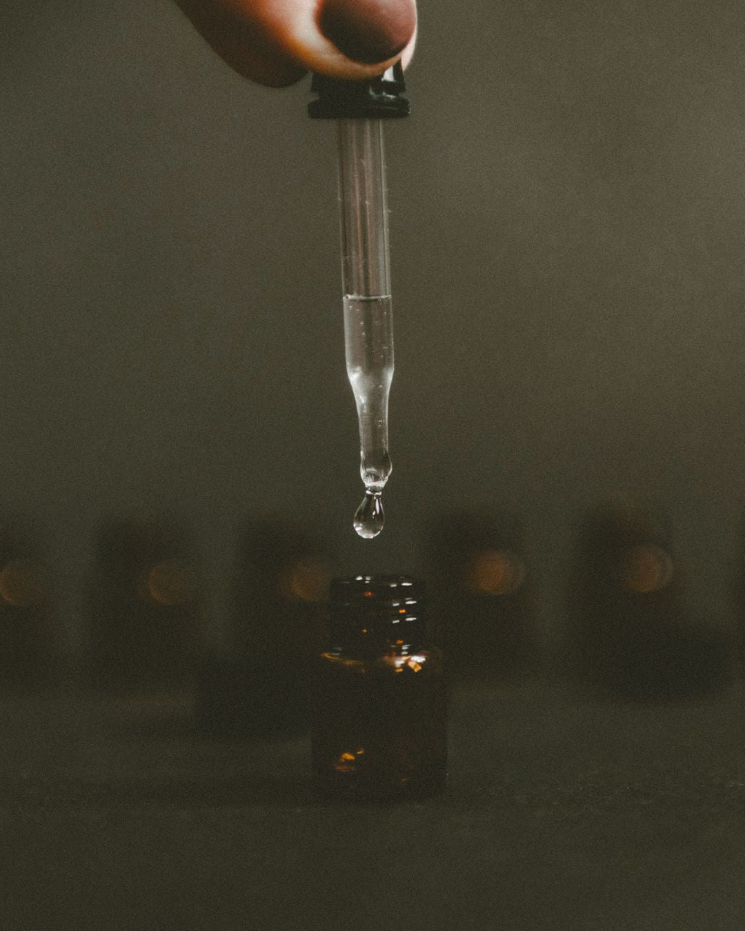 Dark moody image of essential oil bottle with dropper.