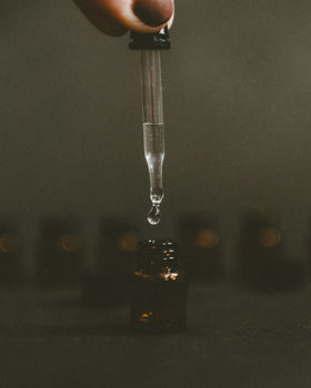 Dark moody image of essential oil bottle with dropper.