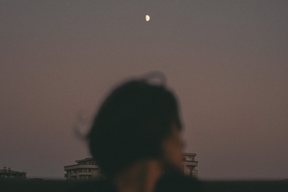 An editorial image of a woman looking back at the moon