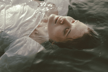 Image of woman floating in water with white linen clothing