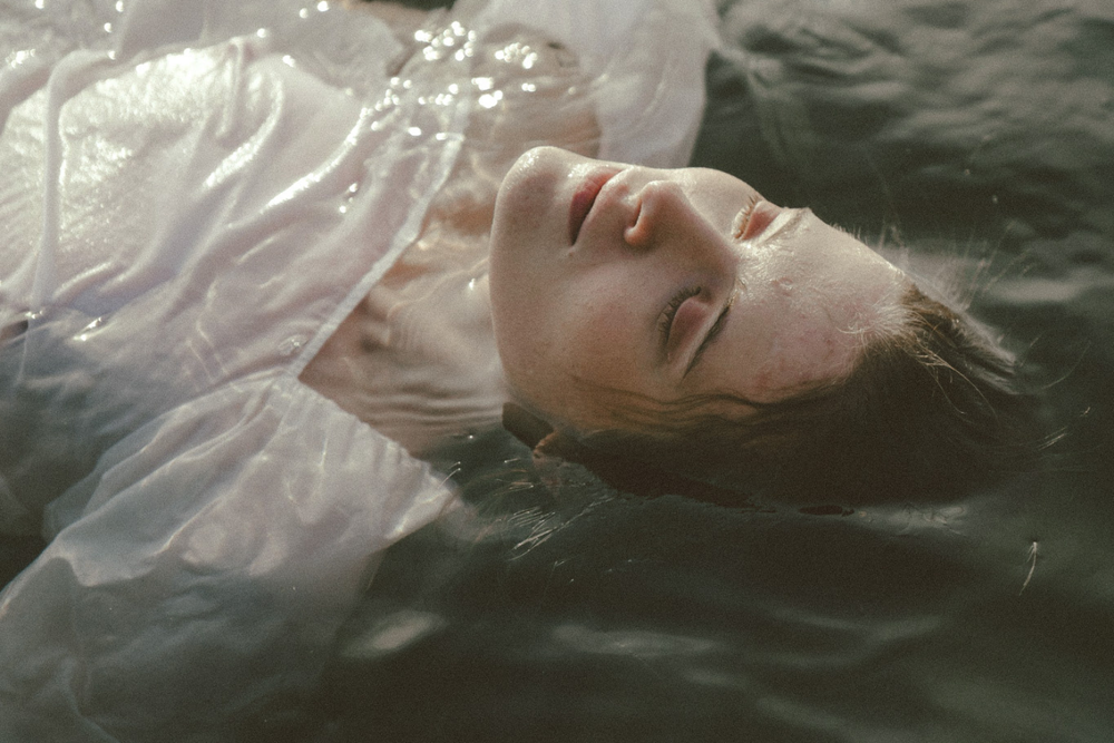 Image of woman floating in water with white linen clothing