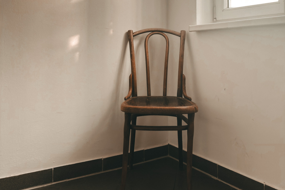 An empty chair in the corner with soft light through the window.