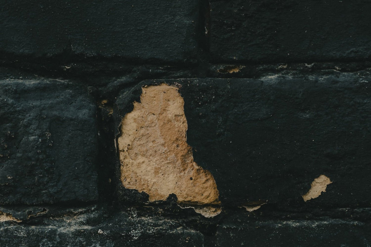 Brick wall surfacing from under old blue paint.
