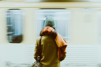 Woman standing in a subway with a train going by at high speed.