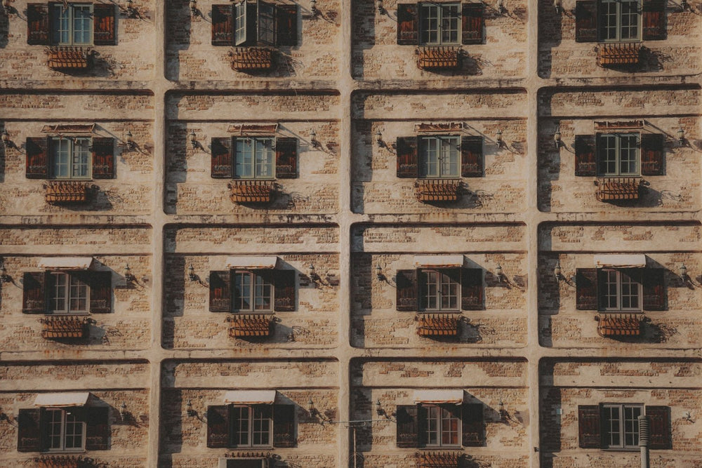 Uniform windows on a neutral stone wall.