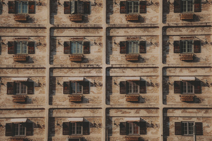 Uniform windows on a neutral stone wall.