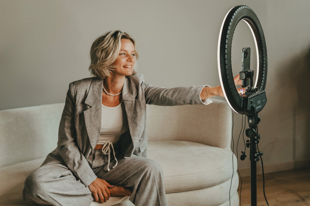 Woman on on a beige sofa with a ring light for content creation.