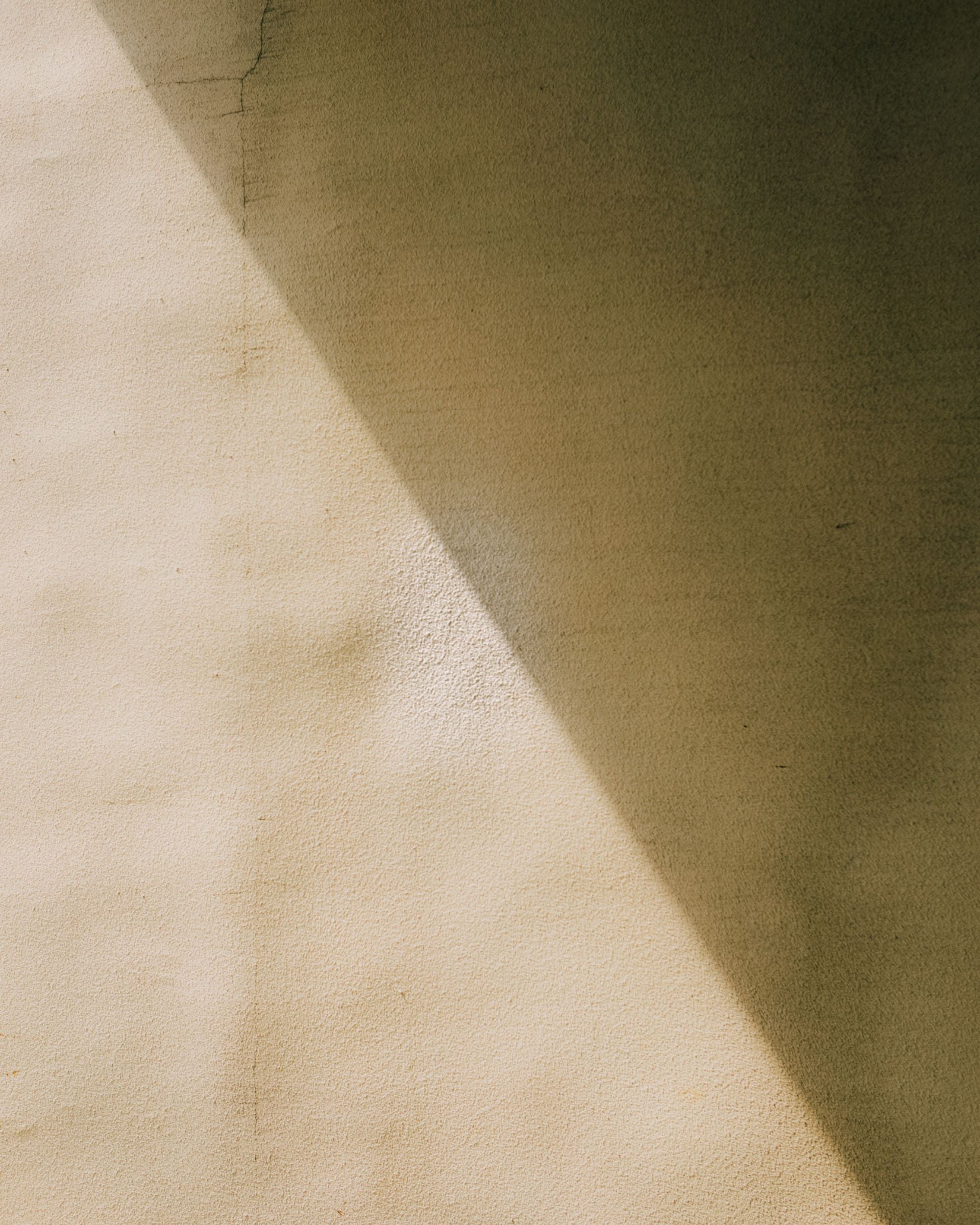 Neutral concrete wall with a sharp shadow across.