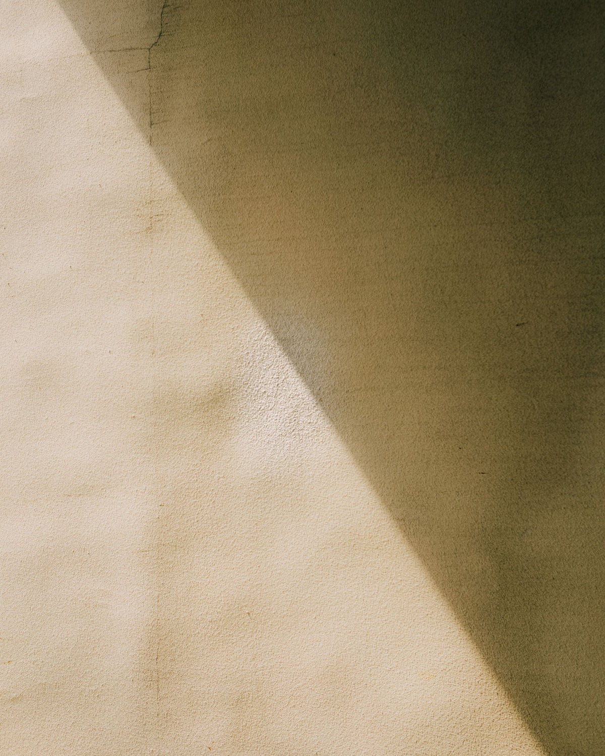 Neutral concrete wall with a sharp shadow across.