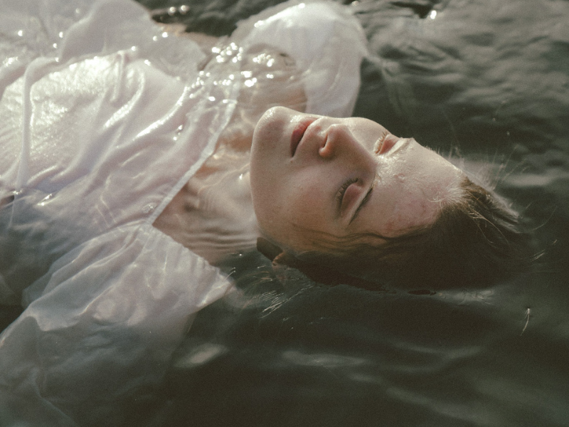 Image of woman floating in water with white linen clothing