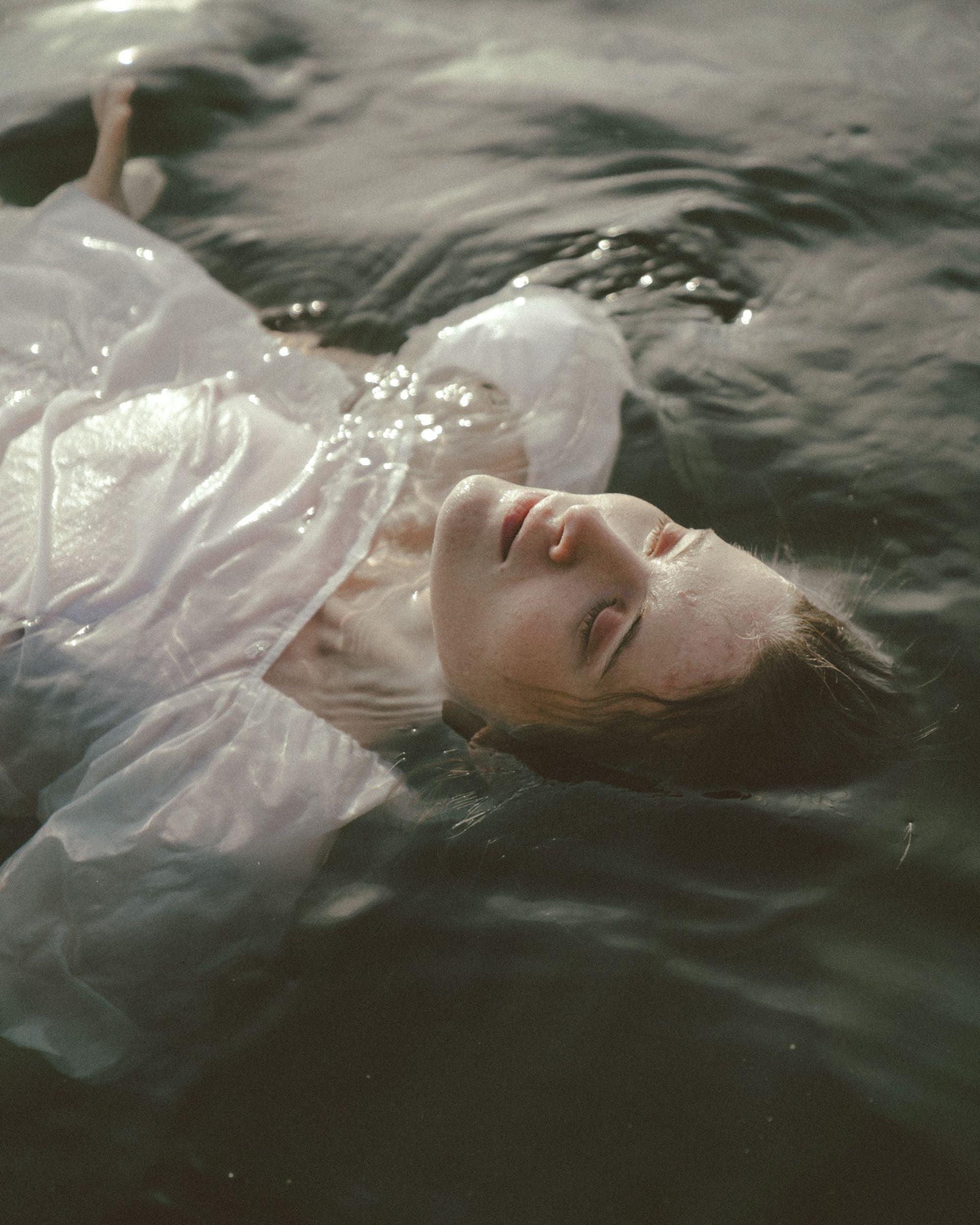 Image of woman floating in water with white linen clothing