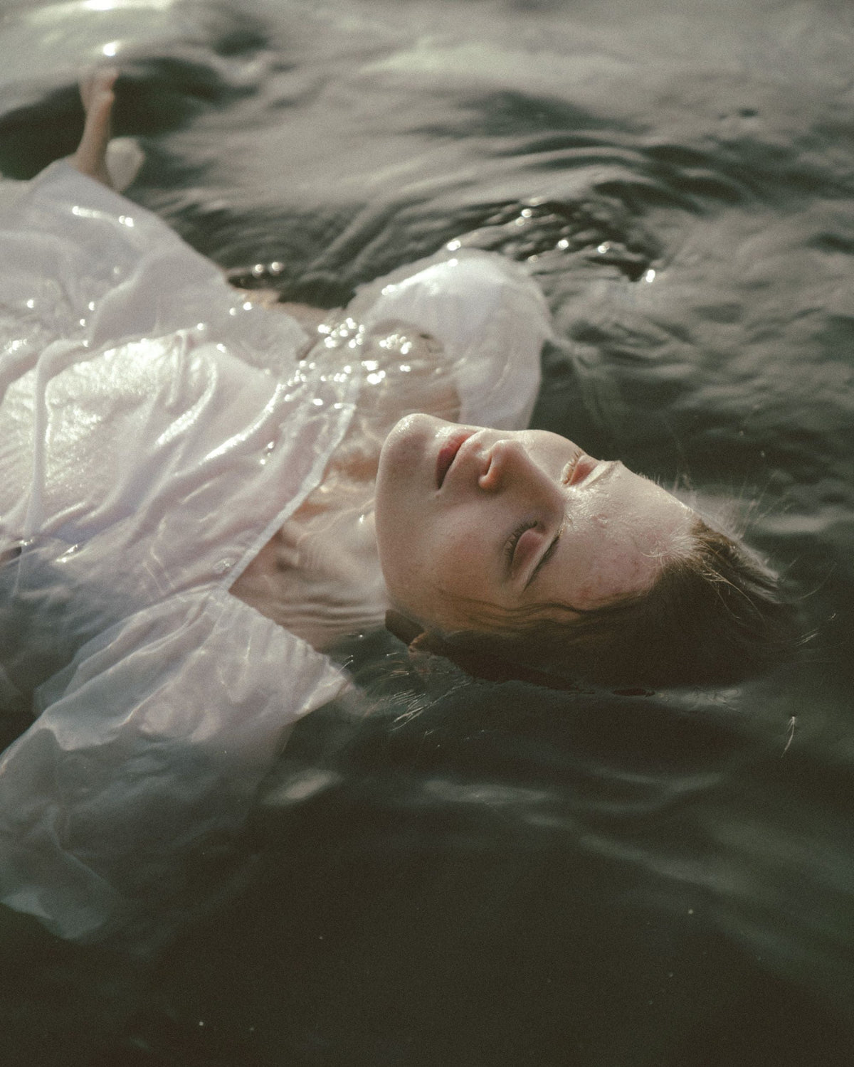 Image of woman floating in water with white linen clothing