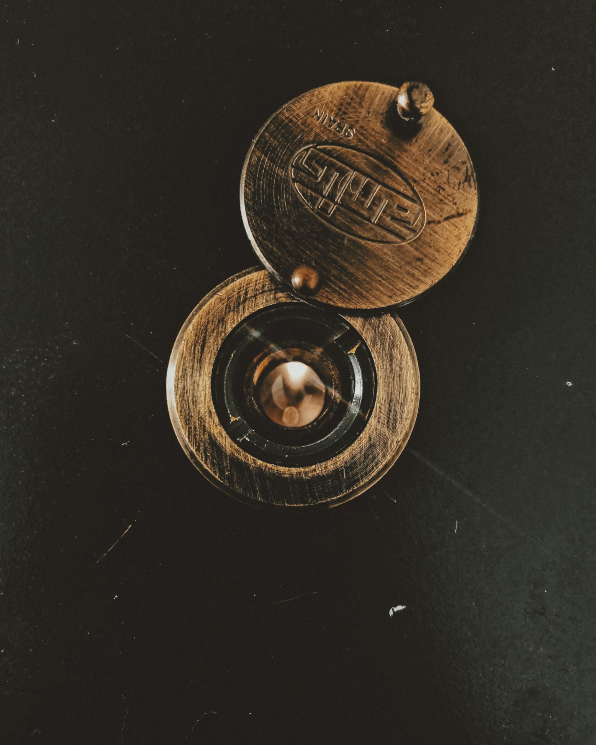 Brass peephole on a dark metal door.