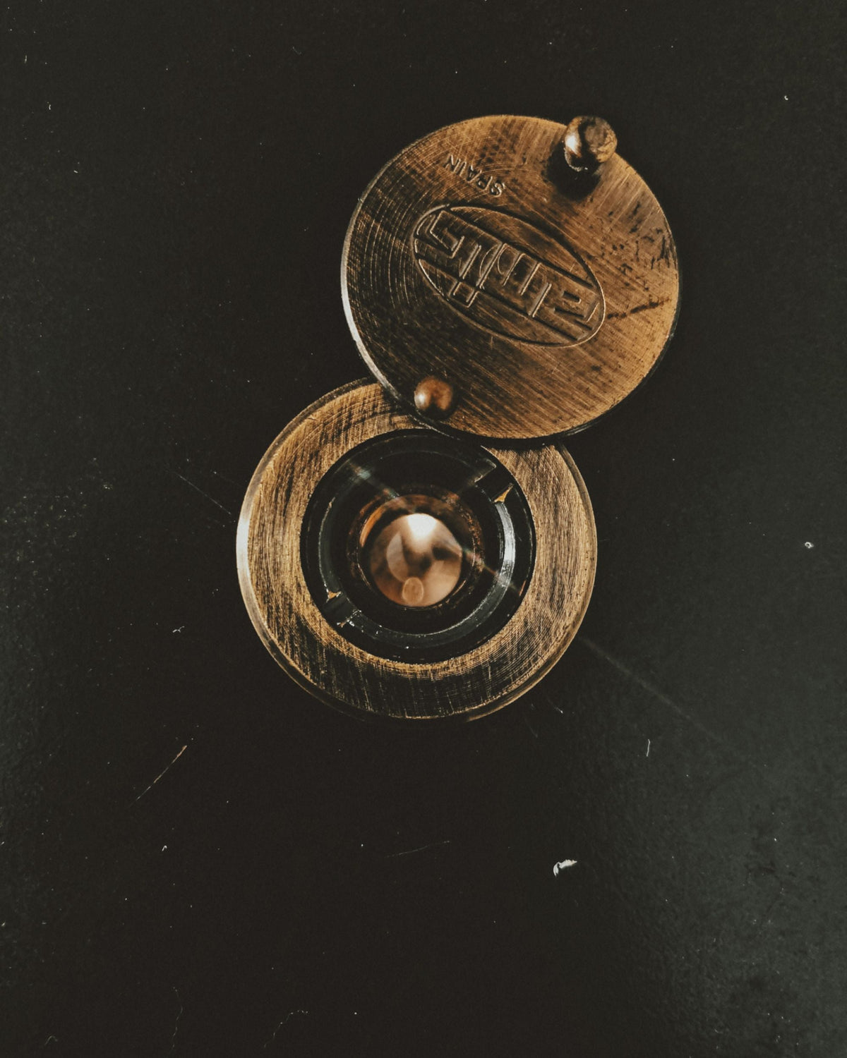 Brass peephole on a dark metal door.