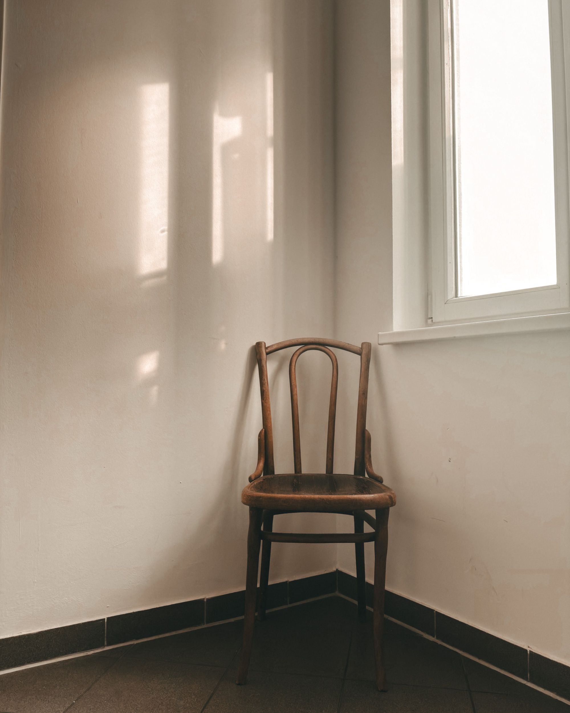 An empty chair in the corner with soft light through the window.