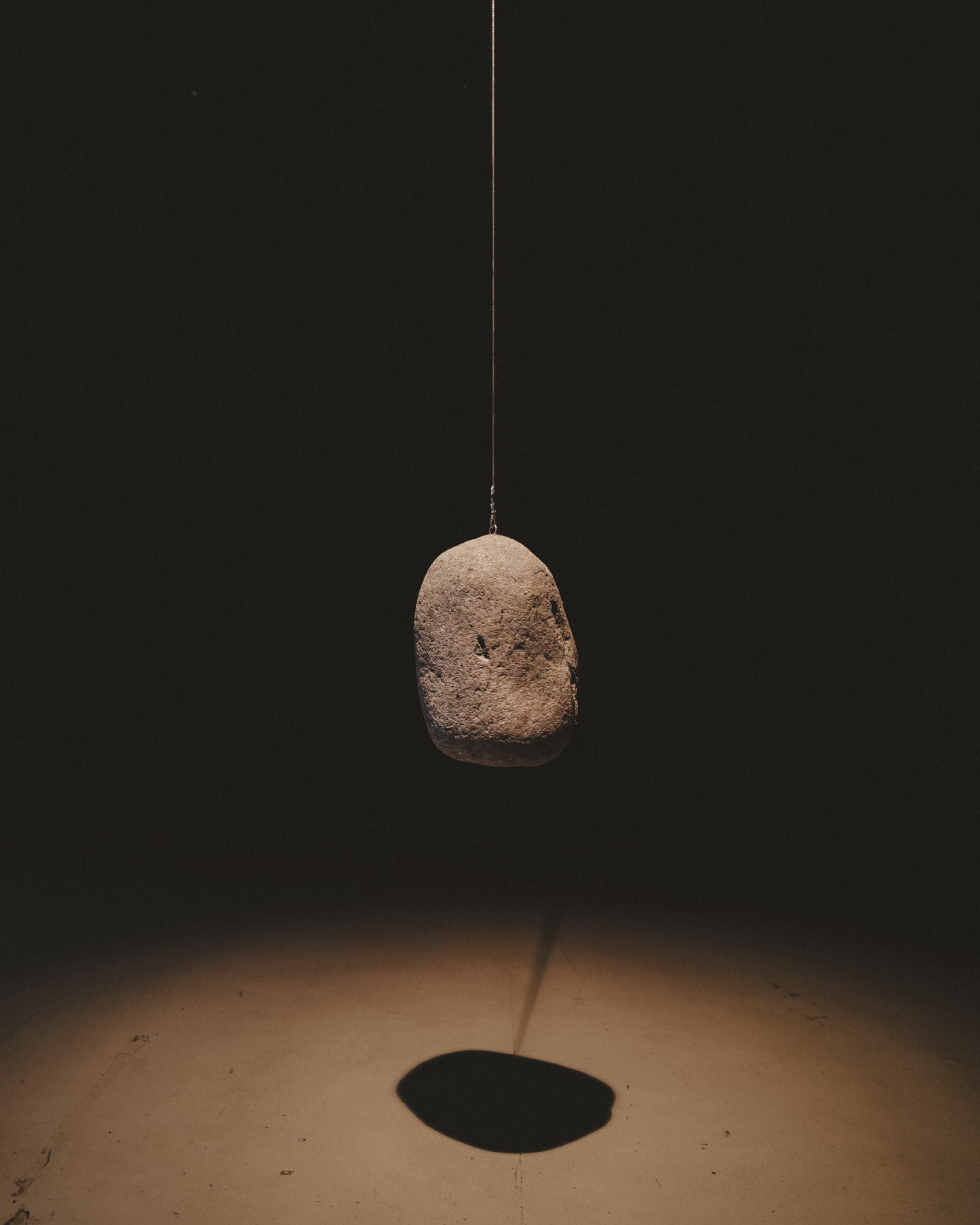 Editorial image of two burning candles and a broken stone plate on a neutral cement surarce.