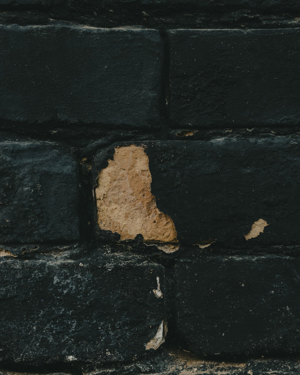 Brick wall surfacing from under old blue paint.