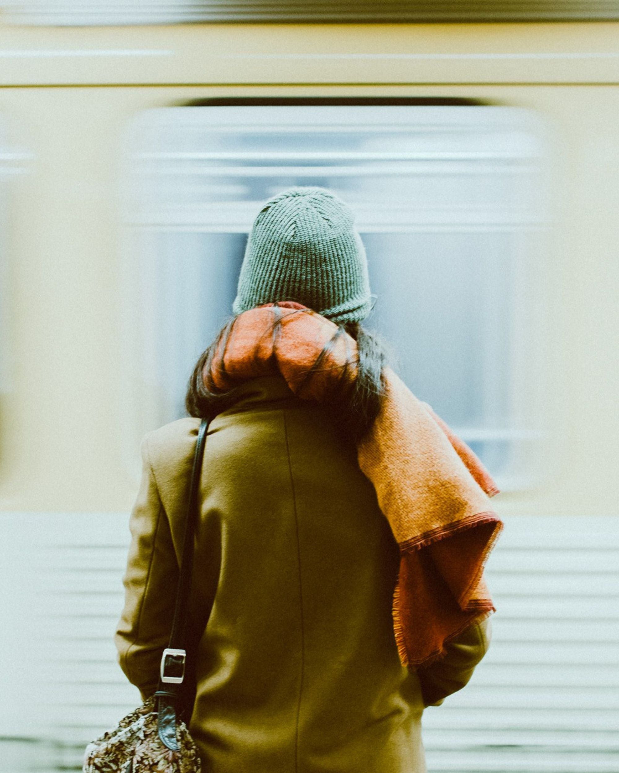 Woman standing in a subway with a train going by at high speed.