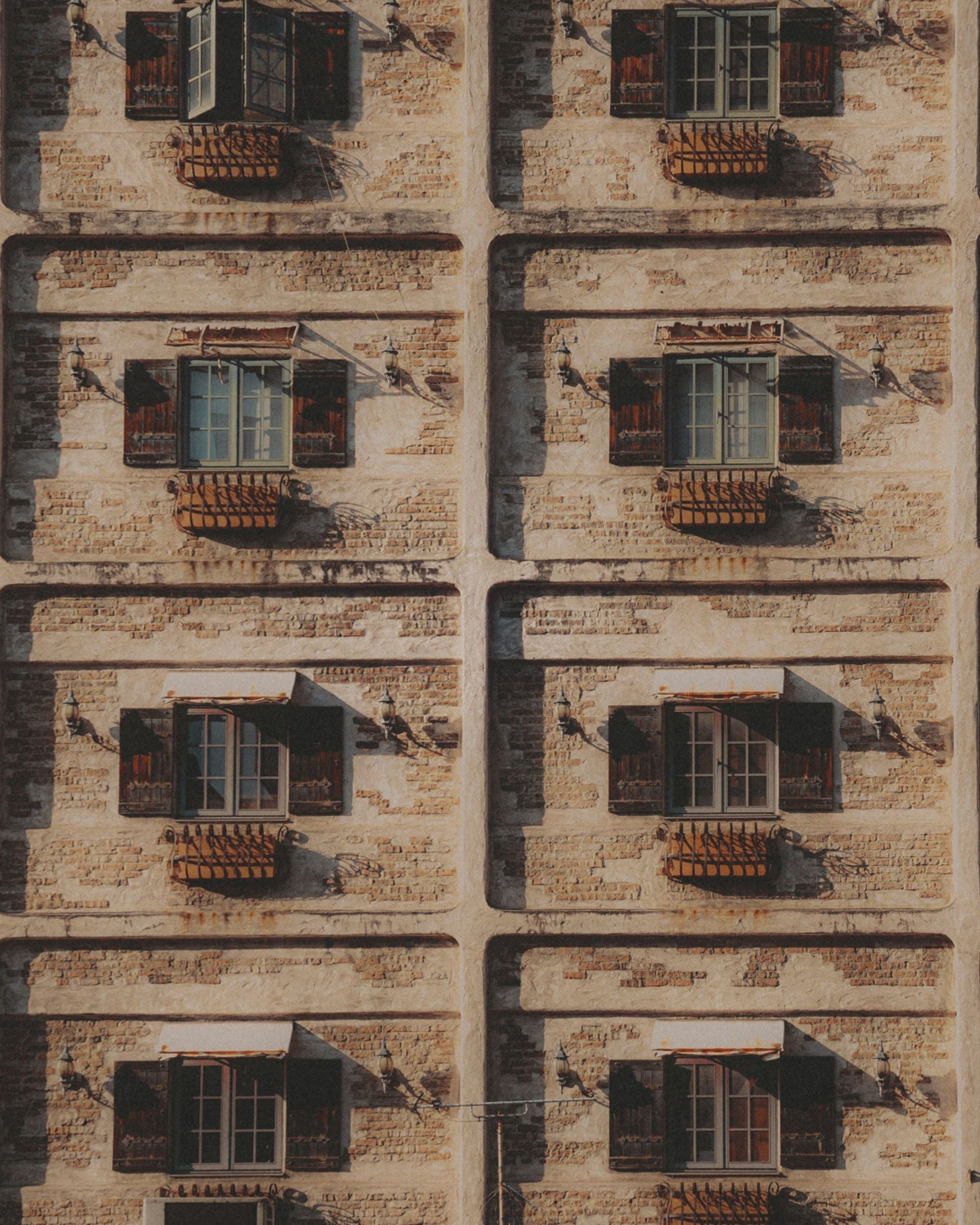 Uniform windows on a neutral stone wall.