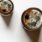 Top view of Abundance ritual candles with green aventurine, botanicals, and gold leaf.