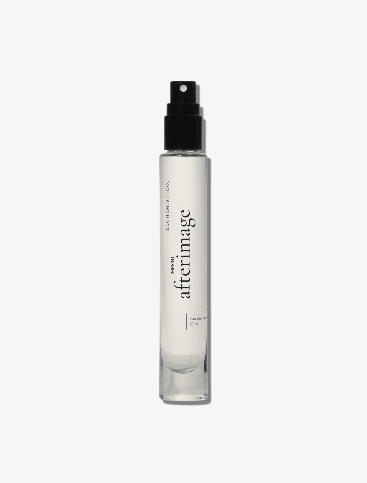A clear glass perfume bottle featuring a white label with the brand name 'Afterimage' by Alchemist + Co.  set against a solid light gray background.