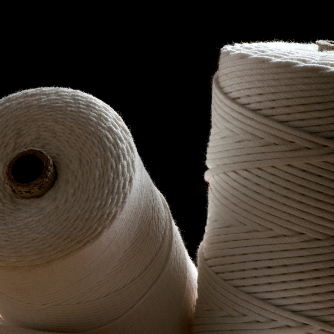 Two spools of white candle wicks on a black background.