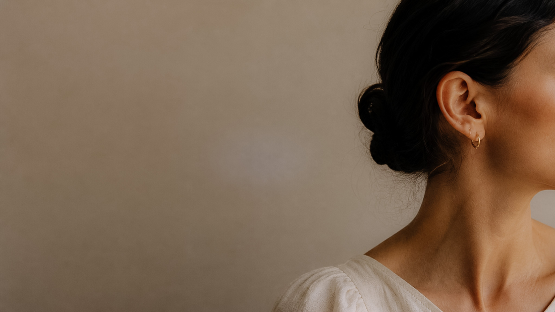Side editorial profile of a woman in soft linen top against a neutral background