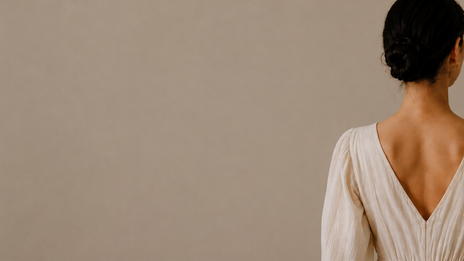 Woman wearing a white dress with a plain beige background.