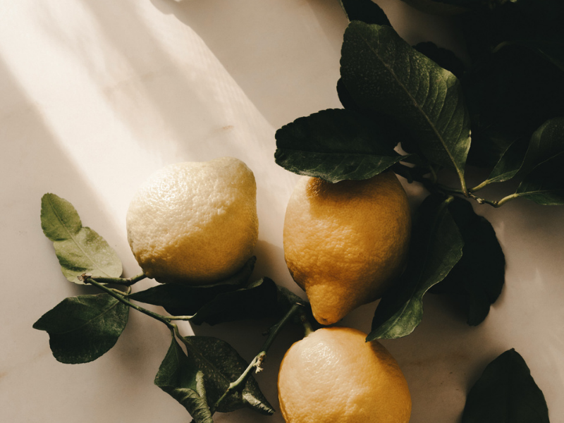 Three lemons with green leaves on a light background.