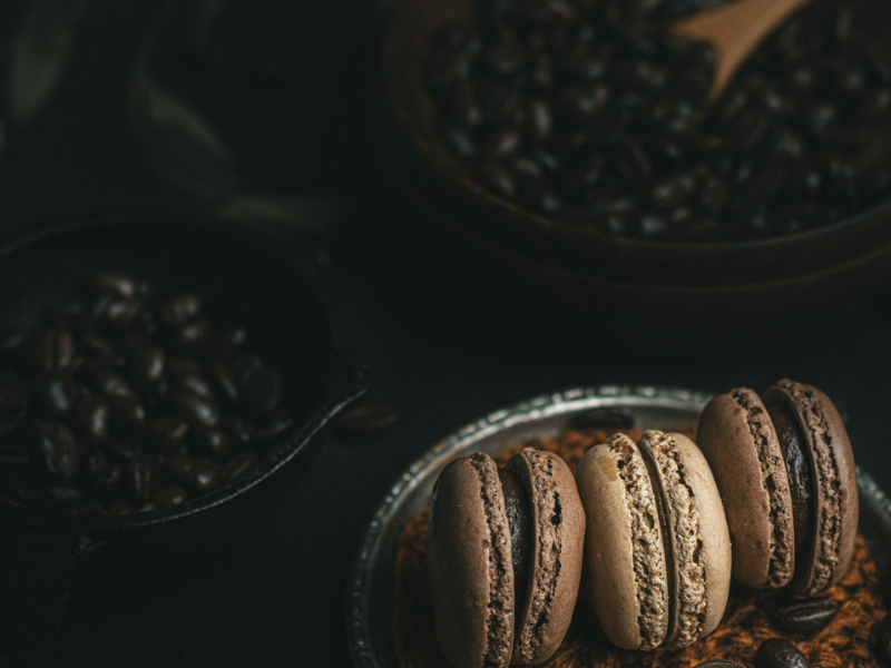 Chocolate macarons with coffee beans on a dark background.
