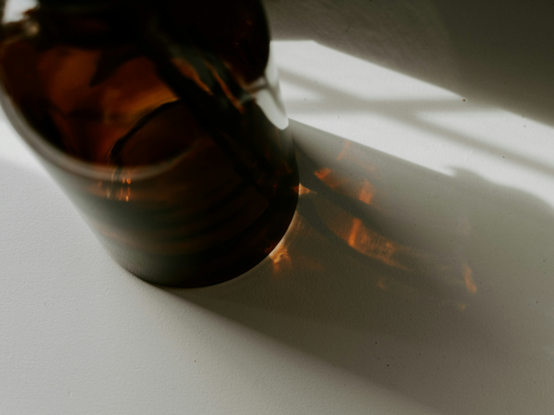 Amber bottle with soft shadows on neutral background.
