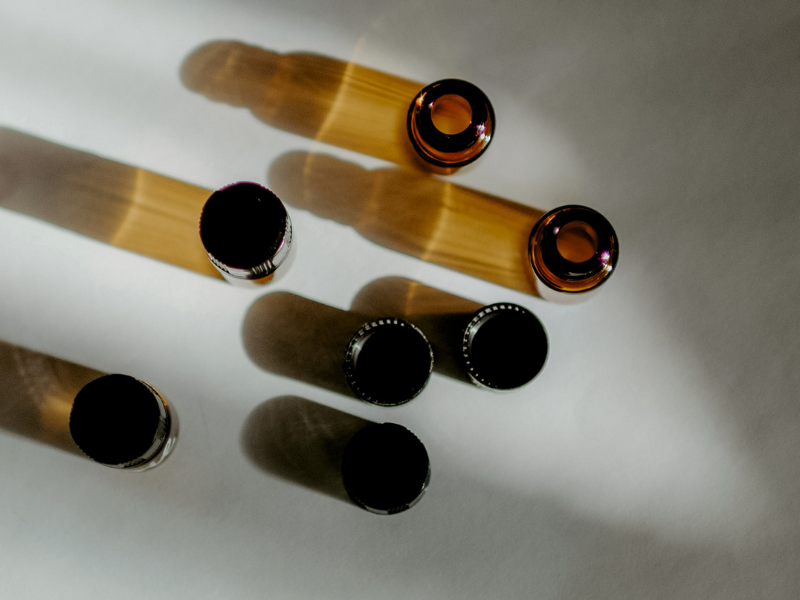 Amber glass bottles with black caps on a reflective surface.