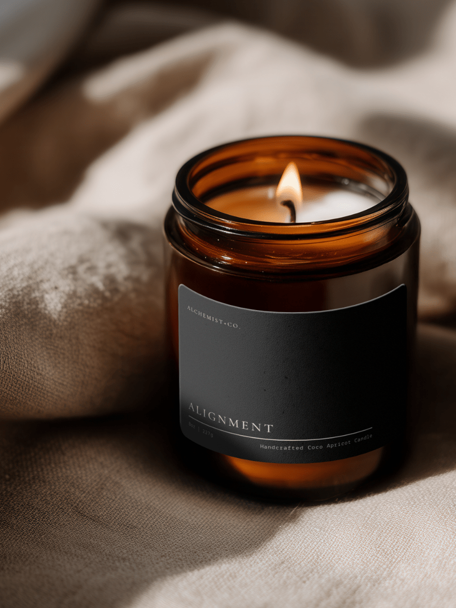 Lit Alignment ritual candle beside textured linen in warm atmospheric light.
