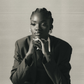 Aquarius woman in a suit sitting in a pensive position against a neutral background.