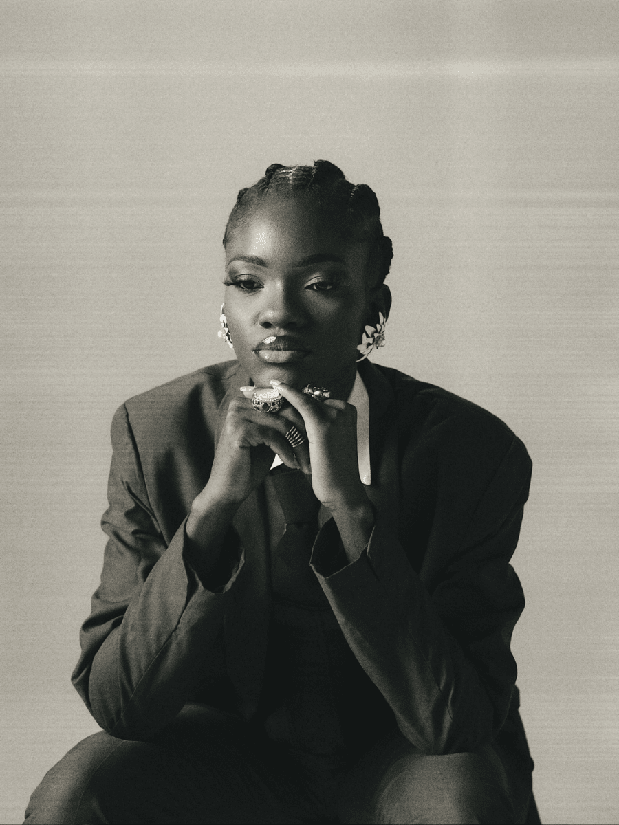Aquarius woman in a suit sitting in a pensive position against a neutral background.
