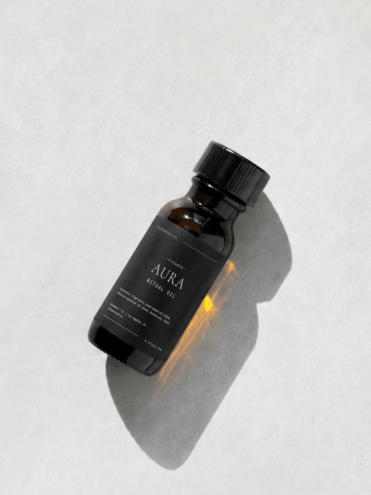 Bottle of "Aura" ritual oil on light gray background.