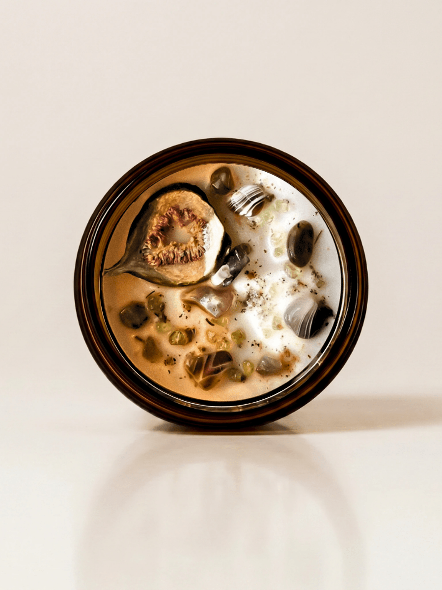 Ayahuasca ritual candle with botswana agate, peridot, quartz, and botanical details viewed from above.