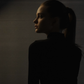 A stoic Capricorn woman in a black turtle neck against dark background with soft light.