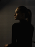 A stoic Capricorn woman in a black turtle neck against dark background with soft light.