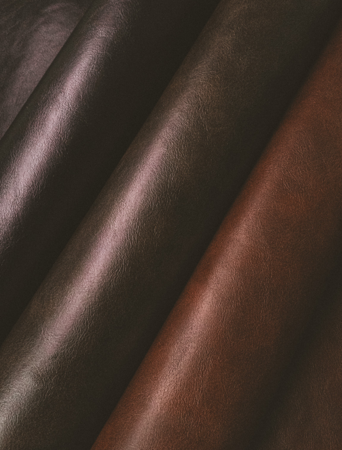 Folds of dark black and oxblood leather catching soft light, the hero note of the Capricorn candle