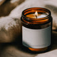 Lit Clarity ritual candle beside textured linen in warm atmospheric light.