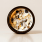 Clarity ritual candle with citrine, rhyolite, and botanical details viewed from above.