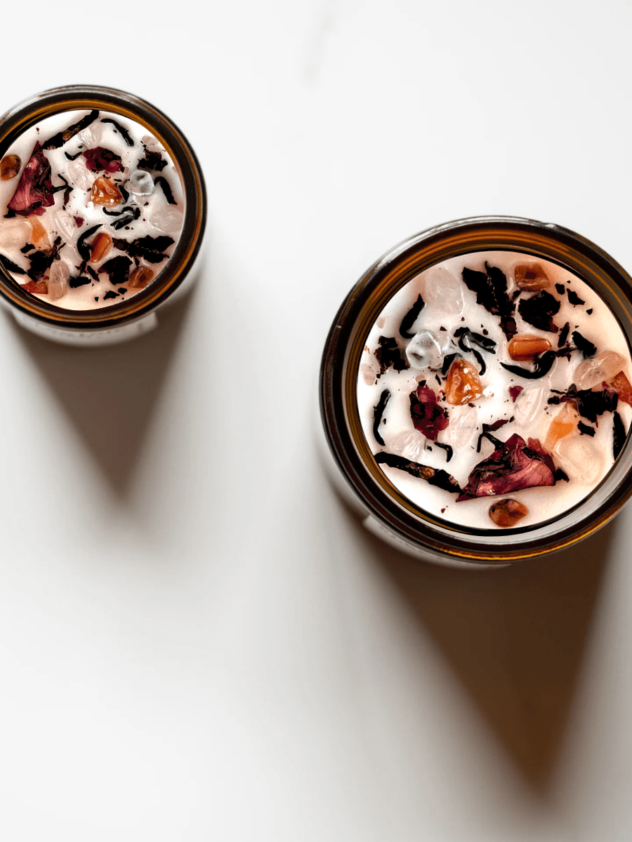 Top view of Dark Feminine ritual candles with carnelian, rose quartz, quartz, and botanicals.