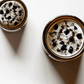 Top view of Divine Masculine ritual candles with black tourmaline, smoky quartz, tigers eye, and botanicals.