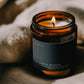 Lit Dragon's Blood ritual candle beside textured linen in warm atmospheric light.