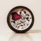 Ethereal ritual candle with rose quartz, hematite, quartz, and botanical details viewed from above.